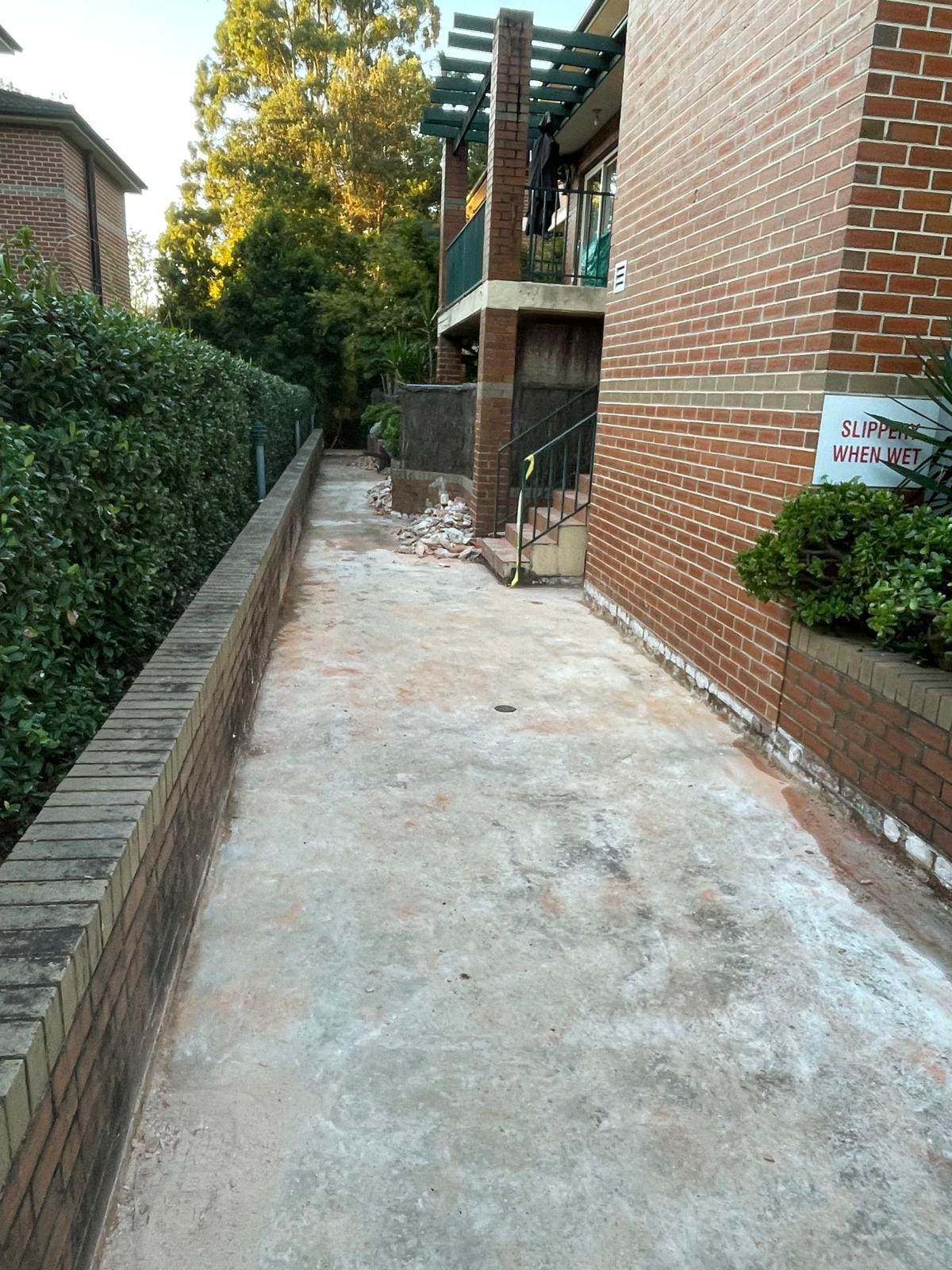 The walkway cleared back to bare concrete and swept clean, ready for setting out, with the old surface gone and the steps beyond untouched.