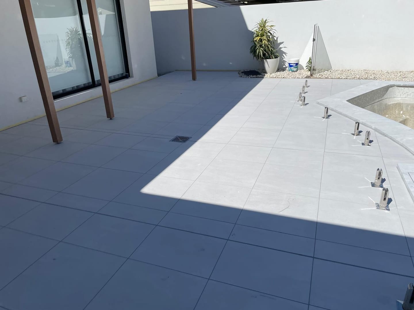Stainless spigots for the glass balustrade set into the finished surface, each one cut in cleanly, with the pool shell curving away beyond.