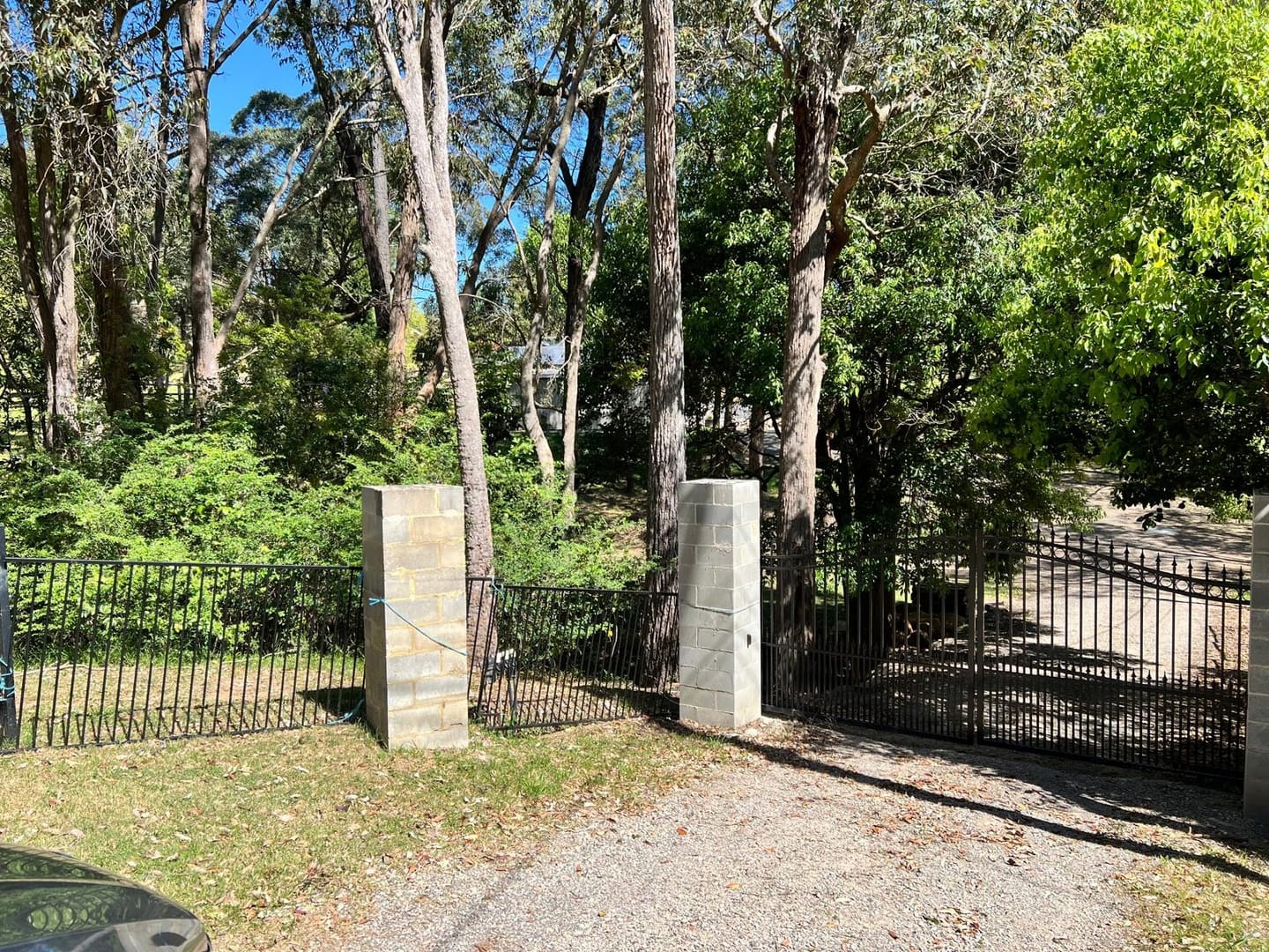 The piers as found: plain grey besser block, unrendered and unclad, with the iron fence running away either side.